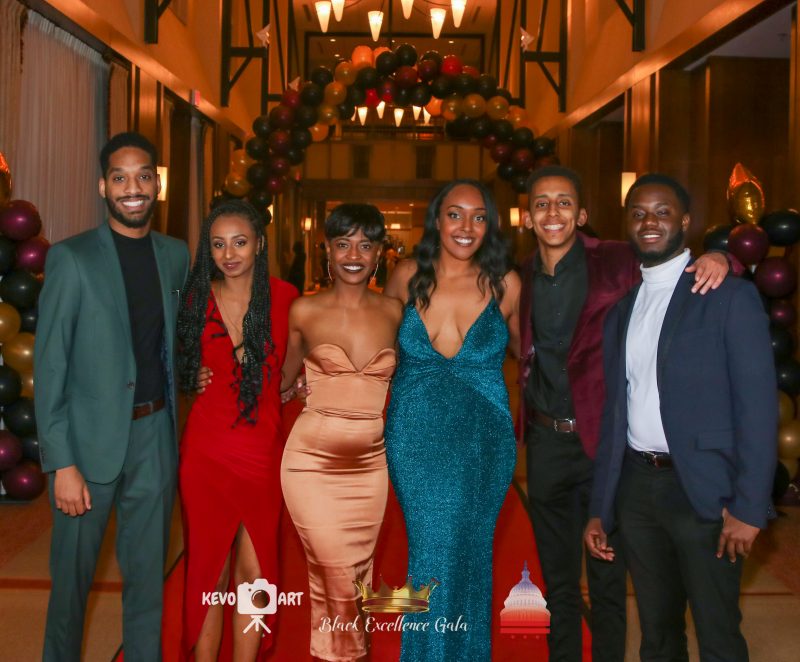 Black Excellence Gala Image from previous Black Excellence Gala event with six people standing side by side with their arms around each other.